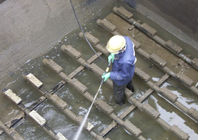 反応槽内の散気板を高圧洗浄機を用いて洗浄する作業員<
